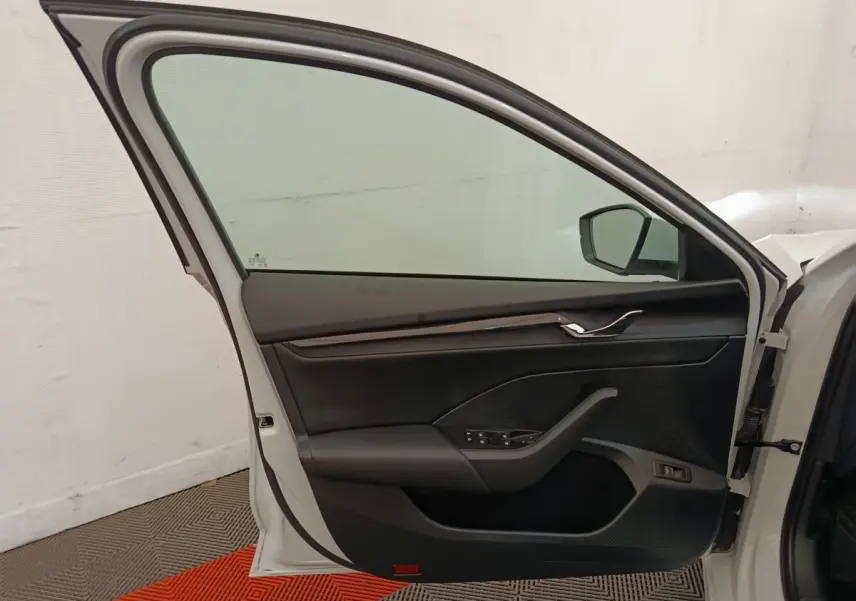 Vue intérieure de la porte avant gauche blanche d'une Skoda Octavia 2023 avec garniture noire et commandes électriques.