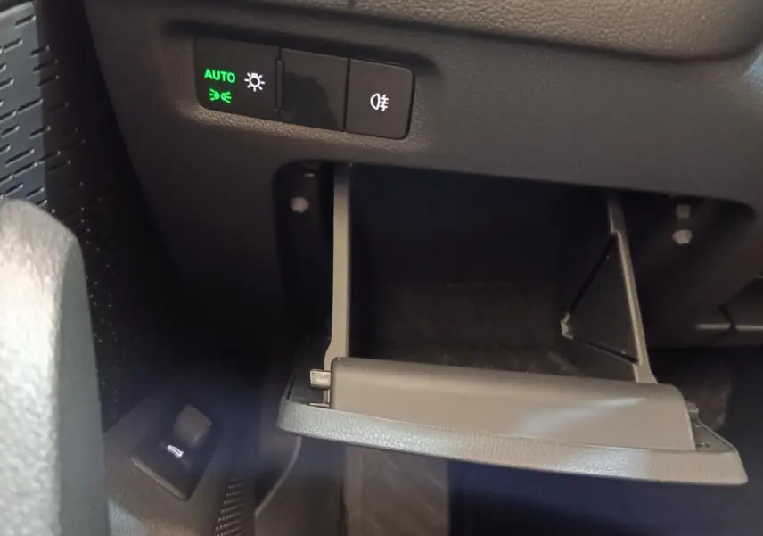 Détail intérieur montrant le tiroir ouvert sous le tableau de bord avec commandes d'éclairage sur une Skoda Octavia 2023.