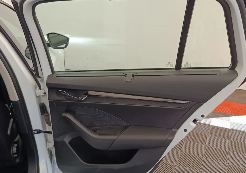 Vue intérieure de la porte arrière gauche blanche d'une Skoda Octavia 2023 avec garniture noire et poignée chromée.
