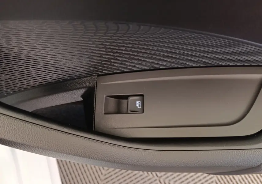 Gros plan sur le bouton de commande de la vitre électrique côté conducteur de la Skoda Octavia blanche 2023.