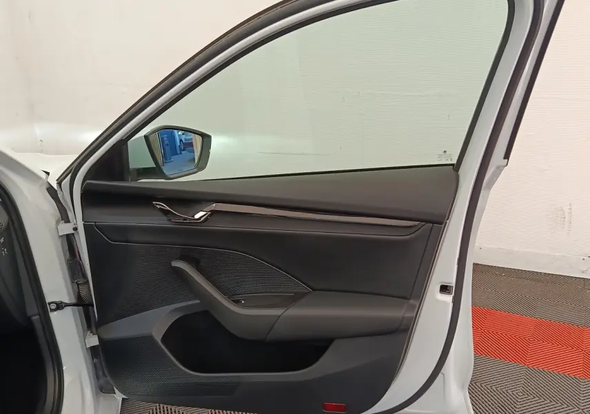 Vue intérieure de la porte avant gauche d'une Skoda Octavia blanche, avec garniture noire et poignée chromée.