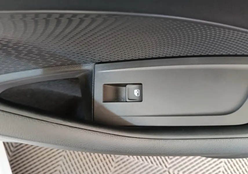 Gros plan sur le bouton d’ouverture de coffre intégré dans la garniture intérieure noire d’une Skoda Octavia 2023.