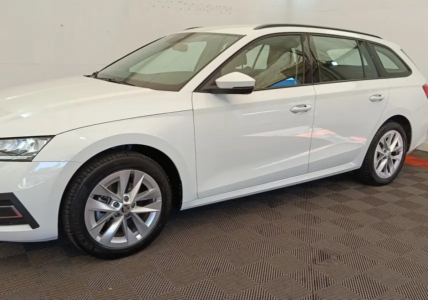 Vue de profil côté gauche d'une Skoda Octavia break blanche 2023 avec jantes alliage et rétroviseurs blancs.