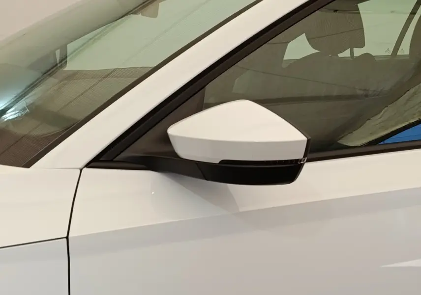 Vue rapprochée du rétroviseur côté conducteur d’une Skoda Octavia blanche 2023 avec vitre teintée.