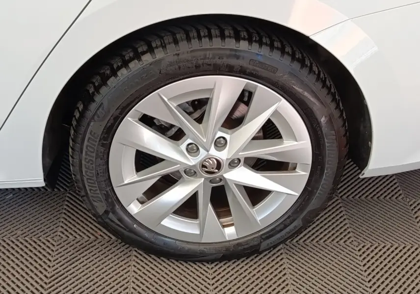 Gros plan sur la roue avant droite d'une Skoda Octavia blanche, mettant en valeur la jante alu à dix branches.