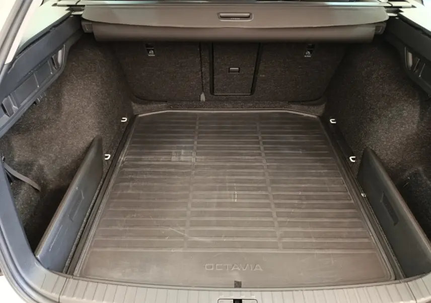 Vue plongeante sur le coffre spacieux noir de la Skoda Octavia 2023 avec tapis de sol marqué Octavia.