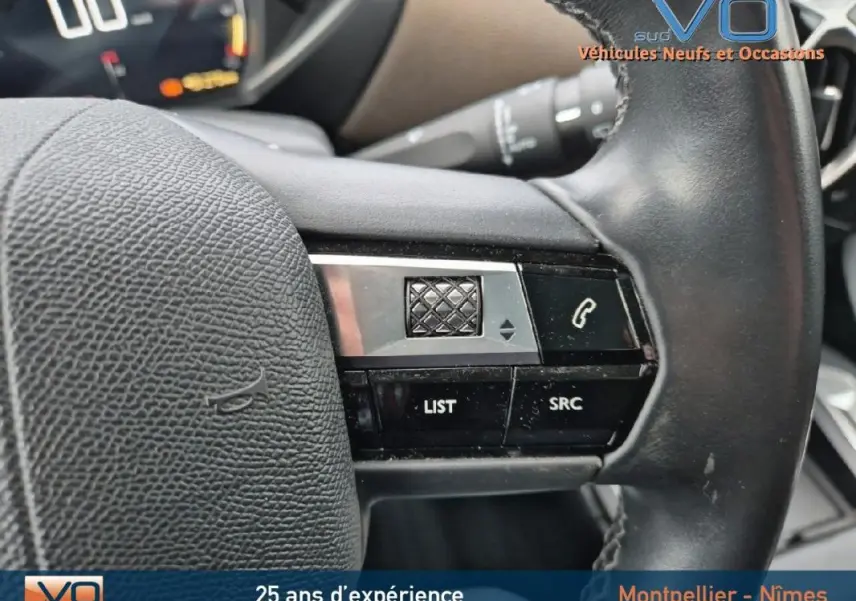 Gros plan sur les commandes au volant noir du DS3 Crossback gris, mettant en valeur les boutons de contrôle audio et téléphone.