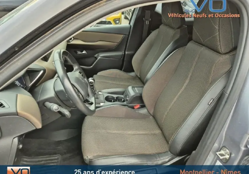 Intérieur avant du DS3 Crossback gris 2020, sièges tissu et cuir, volant multifonction et accoudoir central visible.
