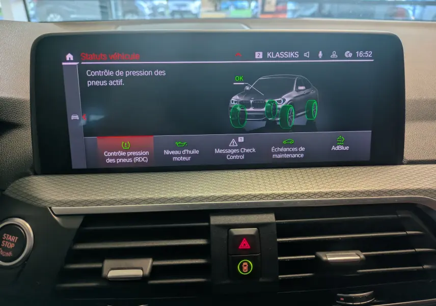 Écran central du tableau de bord BMW X4 blanc 2021 affichant le contrôle actif de la pression des pneus.