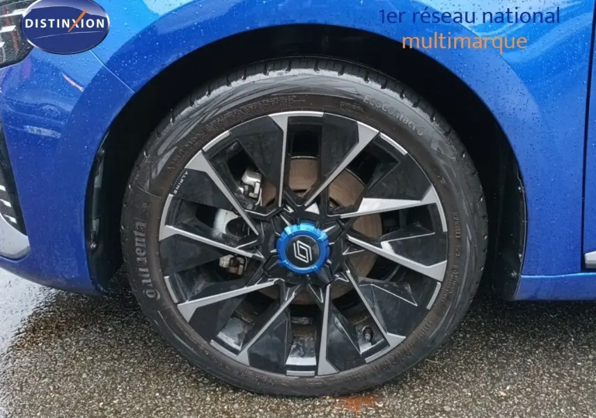 Gros plan sur la roue avant gauche d'une Renault Clio 2024 bleu iron metal avec jante noire et argentée.