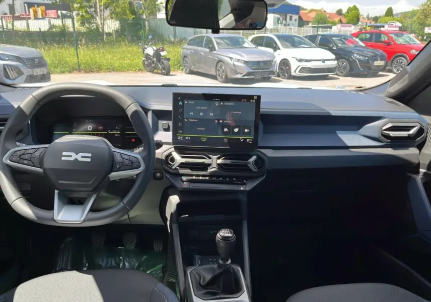 Vue intérieure du tableau de bord et volant du Dacia Bigster blanc glacier 2025, avec écran tactile central et boîte manuelle.