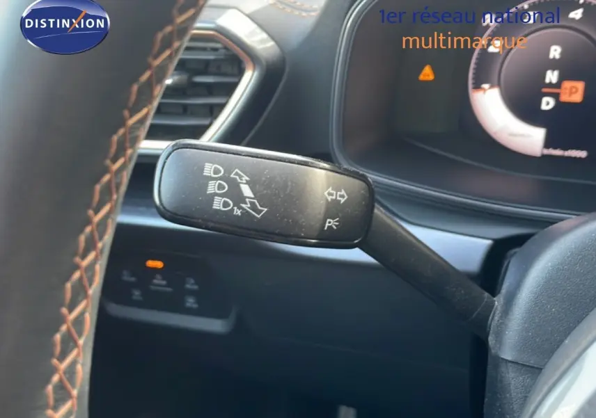 Gros plan sur la manette de clignotant à gauche du volant d’un CUPRA Formentor blanc neige métal, tableau de bord partiellement visible.