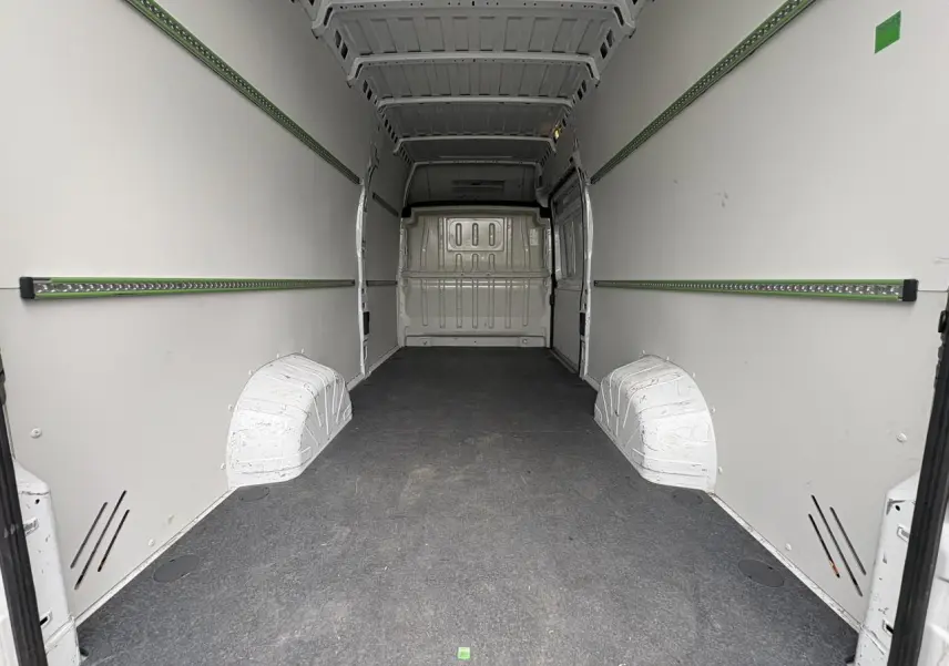 Intérieur du fourgon Opel Movano blanc, vue de l'espace de chargement avec plancher bois et habillage latéral.