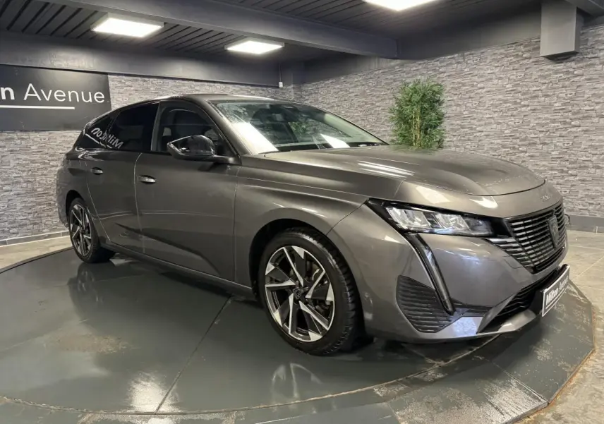 Peugeot 308 SW gris métallisé vue 3/4 avant droit avec calandre noire et jantes alliage 17 pouces.