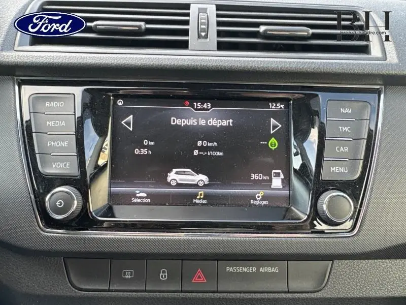 Tableau de bord avec écran tactile central et commandes du système audio d'une Skoda Fabia gris météore, vue de face rapprochée.