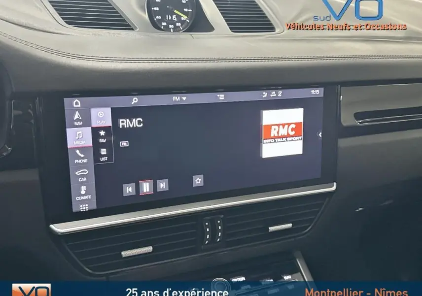 Vue rapprochée de l'écran multimédia noir du tableau de bord du Porsche Cayenne E-Hybrid 2018 affichant la radio RMC.