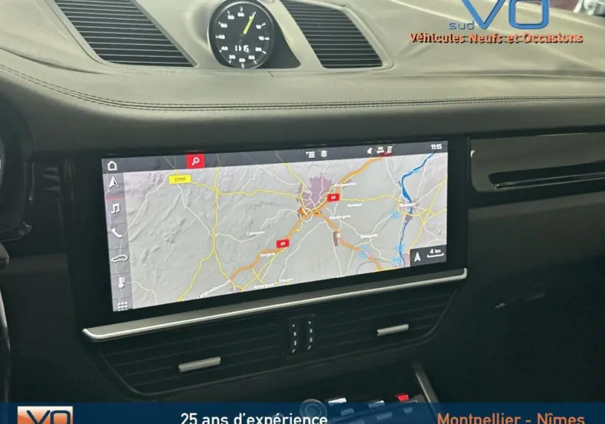Vue intérieure du tableau de bord noir du Porsche Cayenne E-Hybrid 2018 avec écran de navigation et horloge centrale analogique.