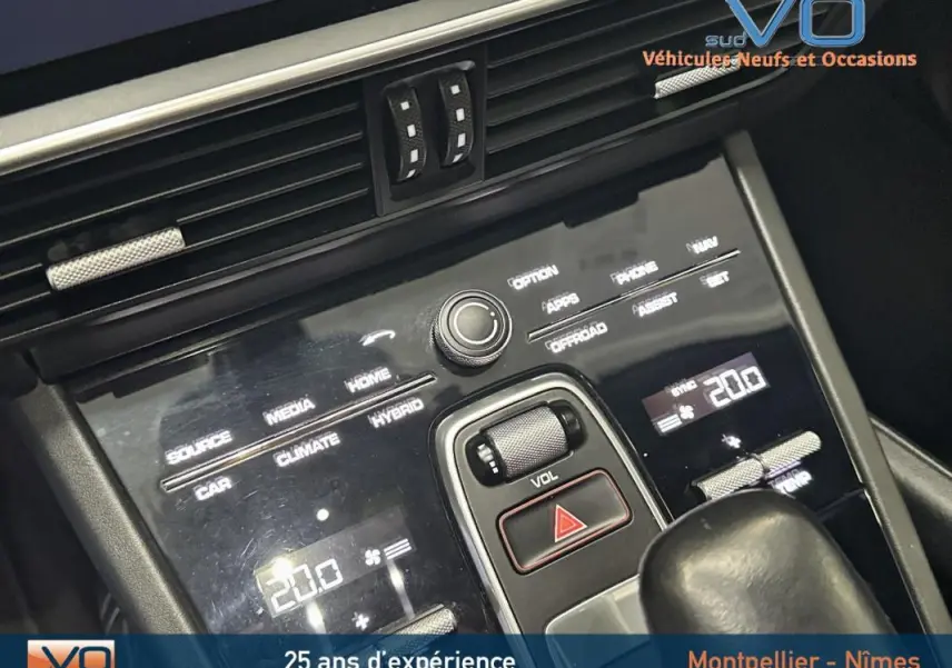 Vue rapprochée de la console centrale noire du Porsche Cayenne E-Hybrid 2018 avec commandes tactiles et molette de volume.