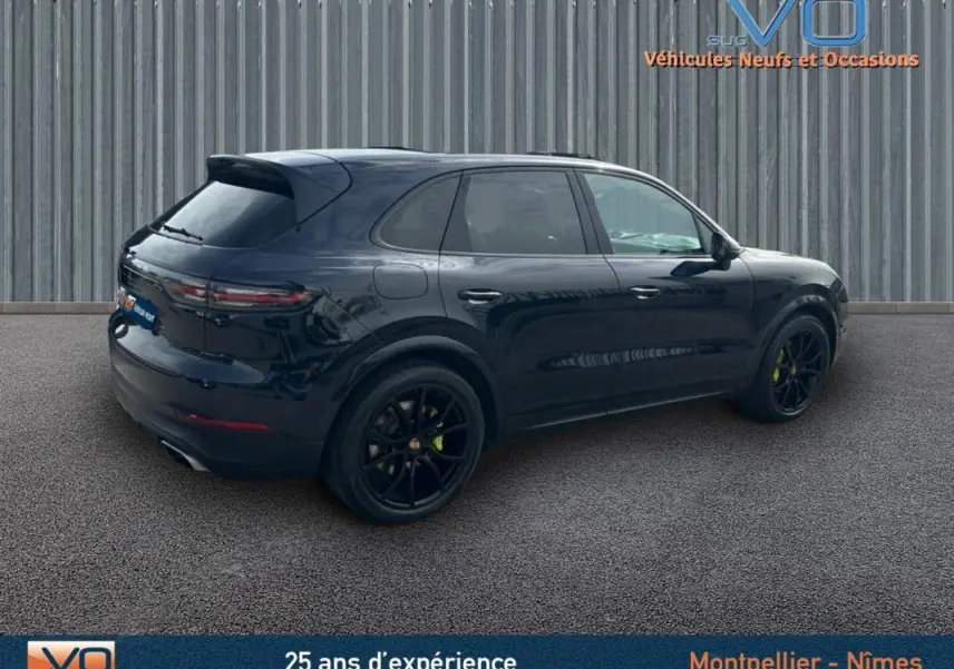 Vue 3/4 arrière droite d'un Porsche Cayenne noir avec jantes noires et feux arrière LED, stationné sur sol gris.