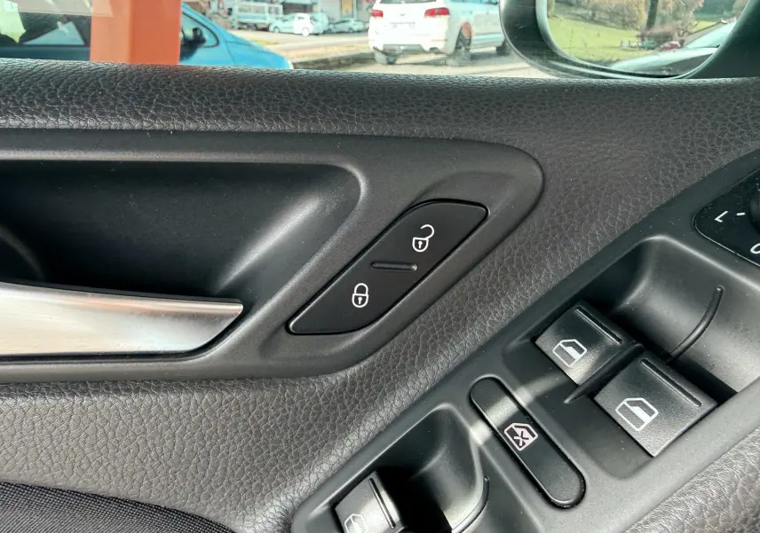 Détail de la porte côté gauche d'une Volkswagen Golf blanche de 2012, montrant les commandes de verrouillage et des vitres électriques.