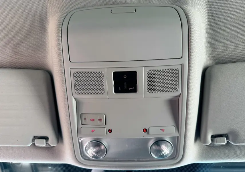 Plafonnier intérieur gris clair avec commandes d'éclairage et haut-parleurs dans une Volkswagen Golf blanche de 2012.