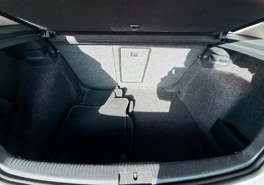 Coffre ouvert d'une Volkswagen Golf 1.4 TSI 122 de 2012, montrant un espace vide avec tapis noirs et revêtement gris.