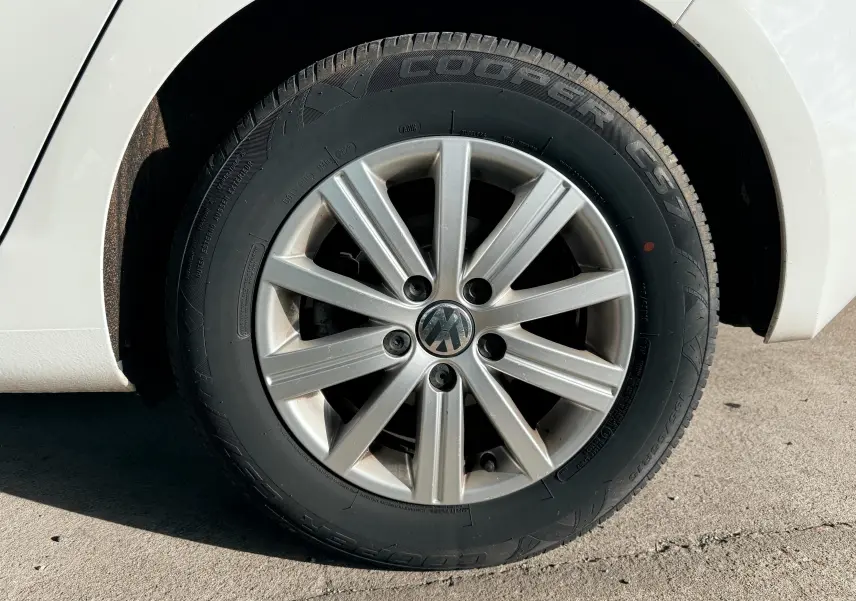 Gros plan sur la roue avant gauche d'une Volkswagen Golf blanche de 2012 avec jante alliage argentée et pneu Cooper.