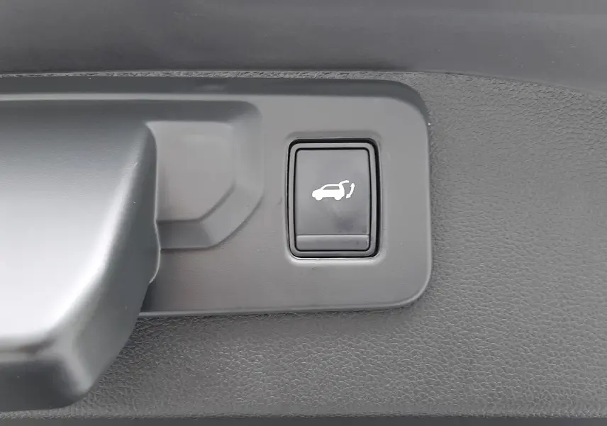 Bouton d'ouverture électrique du hayon sur la partie intérieure du coffre du Renault Austral gris schiste.