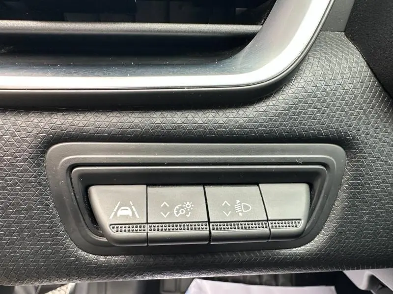 Gros plan sur les boutons de réglage d'assistance et éclairage dans l'habitacle de la Renault Clio 2023 gris schiste.