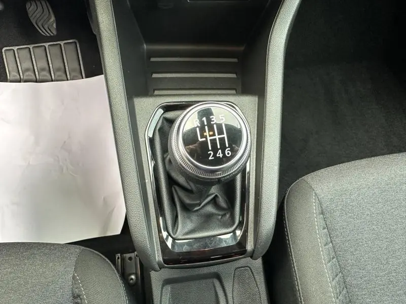 Vue rapprochée du levier de vitesses manuel noir dans une Renault Clio 2023, finition Gris Schiste, intérieur tissu gris.