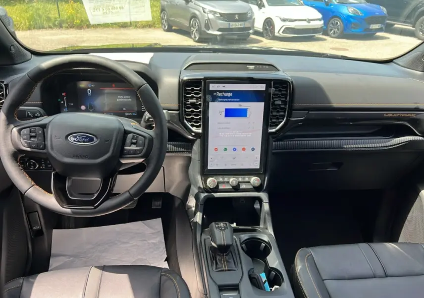 Intérieur du Ford Ranger Wildtrak 2026, vue du poste de conduite avec écran central vertical et volant cuir multifonctions.