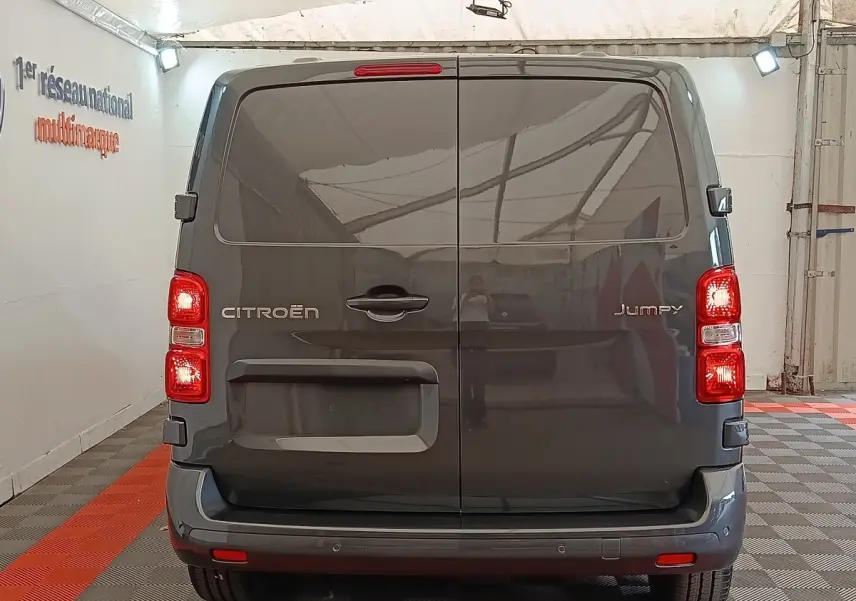 Vue arrière du Citroën Jumpy gris foncé 2025 avec portes battantes et feux arrière allumés dans un garage.