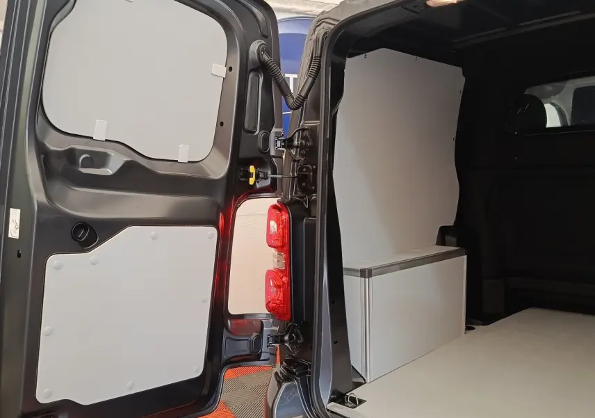 Vue intérieure arrière du Citroën Jumpy gris foncé, montrant la cloison pleine et l'espace de chargement aménagé.