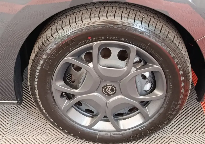 Gros plan sur la roue arrière droite d’un Citroën Jumpy gris foncé, montrant le pneu et l’aile du véhicule.