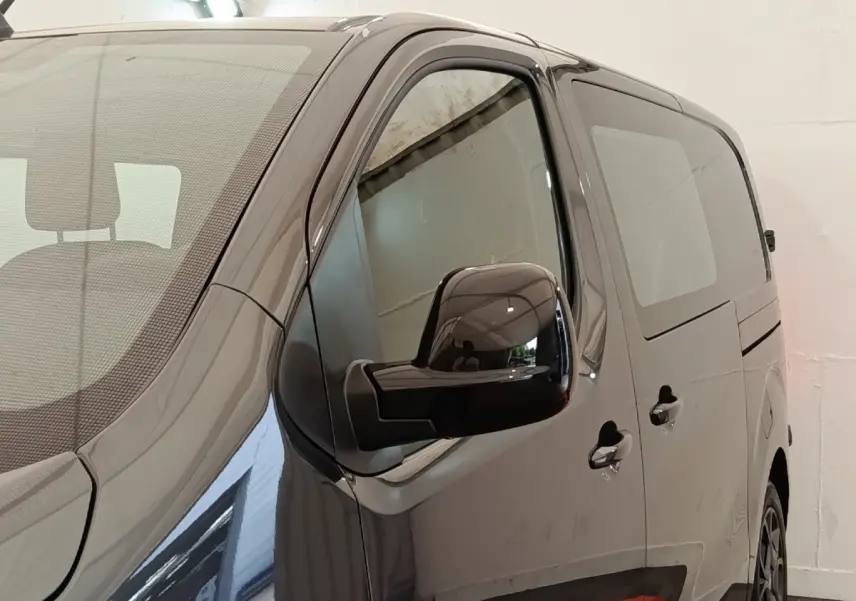 Vue de côté droit en gros plan d’un Citroën Jumpy gris foncé avec rétroviseur noir brillant et vitres teintées.