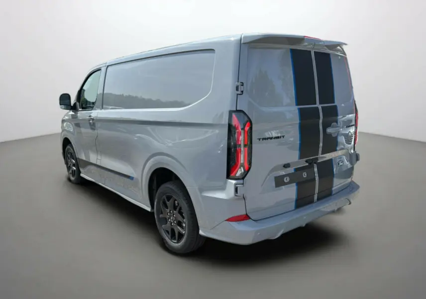 Vue 3/4 arrière droite du Ford Transit Fourgon Custom gris mat avec bandes noires sportives et jantes alu noires.