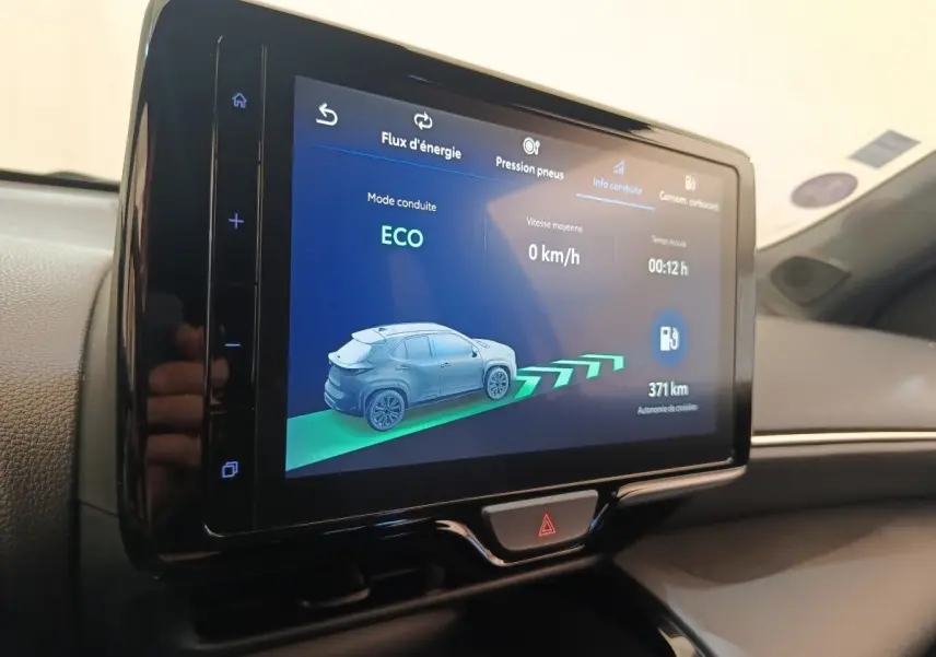 Écran tactile central affichant le mode ECO et l'autonomie de 371 km dans l'habitacle d'une Toyota Yaris Cross blanche.