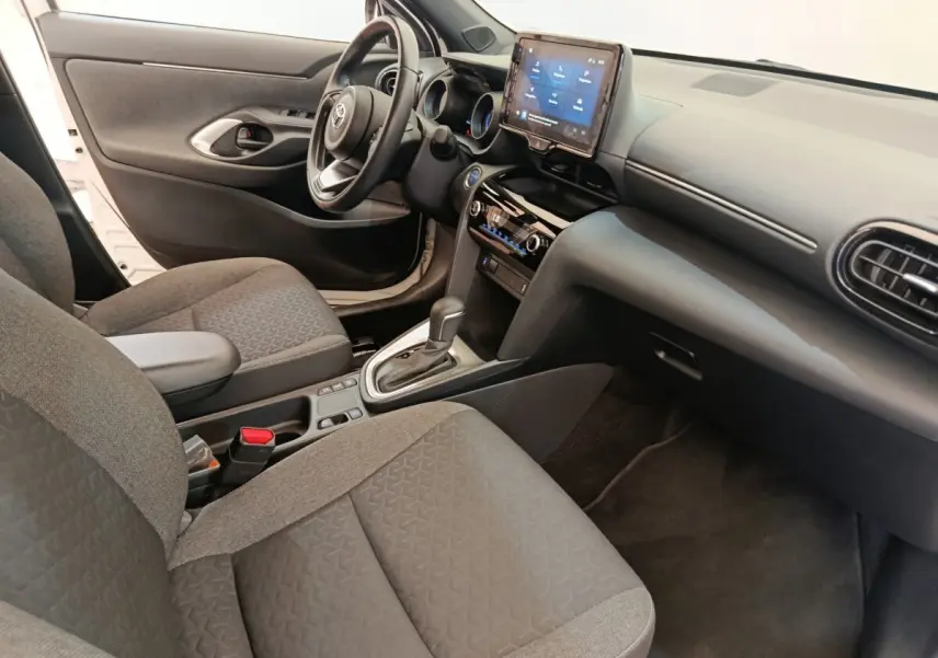 Vue intérieure côté conducteur de la Toyota Yaris Cross blanche 2022, avec tableau de bord et écran tactile central.