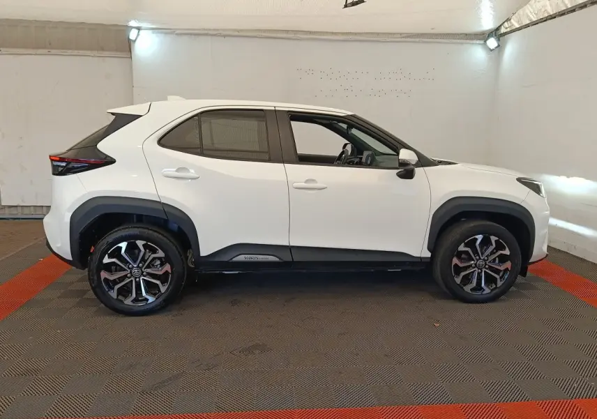 Profil droit d'une Toyota Yaris Cross blanche 2022 avec jantes alliage noires et détails noirs sur les bas de caisse.