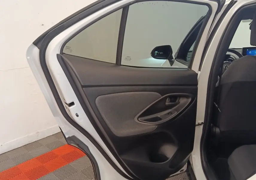 Vue intérieure de la porte arrière gauche ouverte d'une Toyota Yaris Cross blanche, avec garniture noire et grise.