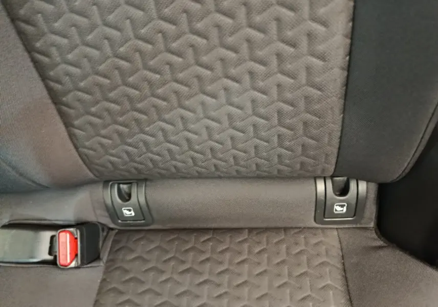 Détail de la banquette arrière noire de la Toyota Yaris Cross avec fixation Isofix et boucle de ceinture rouge visible.