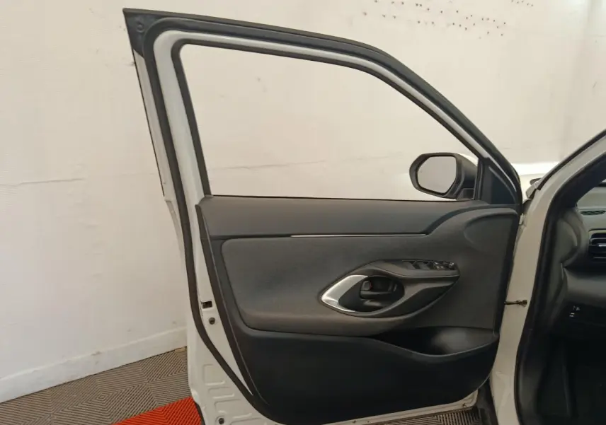 Vue intérieure de la porte avant droite blanche d'une Toyota Yaris Cross 1.5 Hybrid 2022 avec garniture noire et commandes.