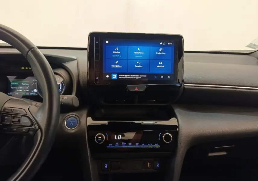 Vue intérieure centrée sur le tableau de bord noir de la Toyota Yaris Cross hybride avec écran tactile allumé.