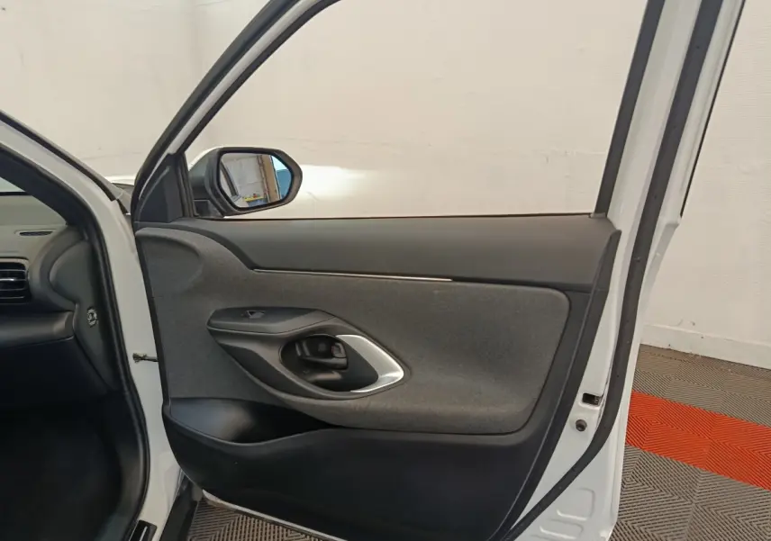 Vue intérieure de la porte avant gauche blanche d'une Toyota Yaris Cross 2022 avec garniture grise et noire.