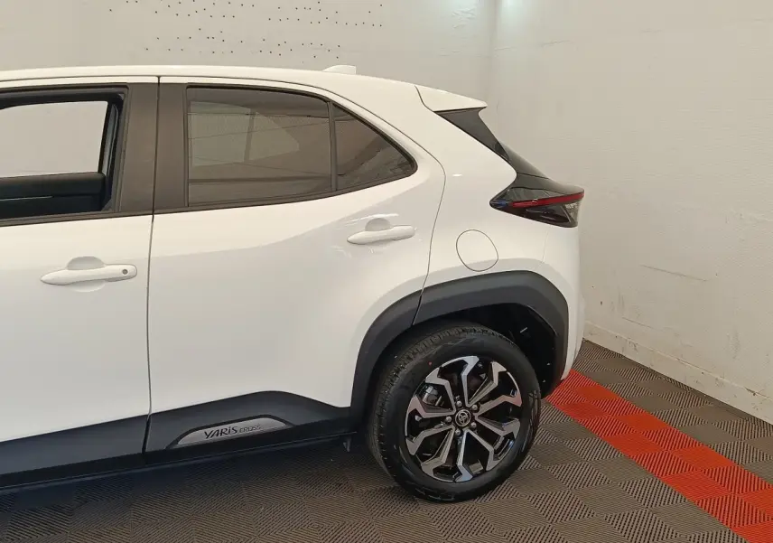 Vue côté arrière droit de la Toyota Yaris Cross blanche, soulignant les jantes alliage et les détails noirs autour des passages de roue.