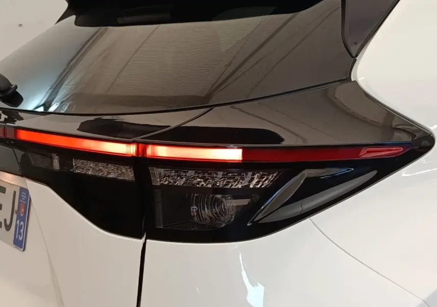 Gros plan sur le feu arrière droit allumé d’une Toyota Yaris Cross blanche, soulignant le contraste noir et blanc du hayon.