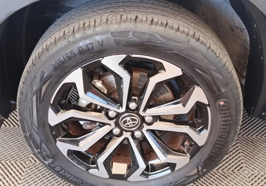 Gros plan sur la roue avant droite avec jante alliage noire et argentée du Toyota Yaris Cross blanc 2022.