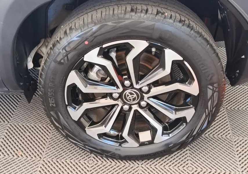 Gros plan sur la jante noire et argentée avec logo Toyota d’un pneu Continental monté sur une Toyota Yaris Cross blanche.