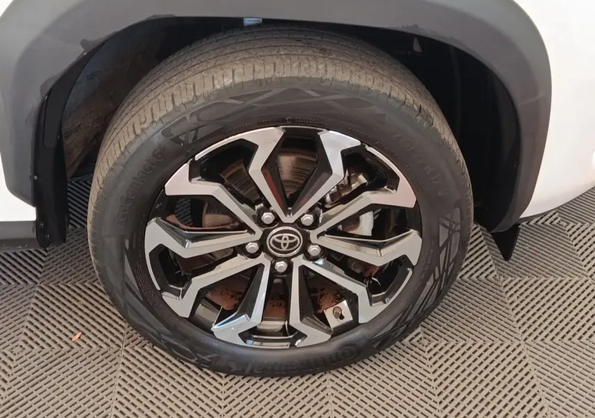 Gros plan sur la roue avant droite de la Toyota Yaris Cross blanche avec jante alliage noire et argentée.