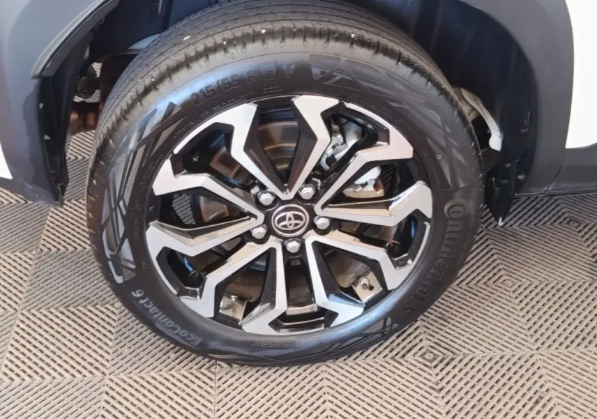 Gros plan sur la roue avant droite de la Toyota Yaris Cross blanche, mettant en valeur la jante noire et argentée au design moderne.